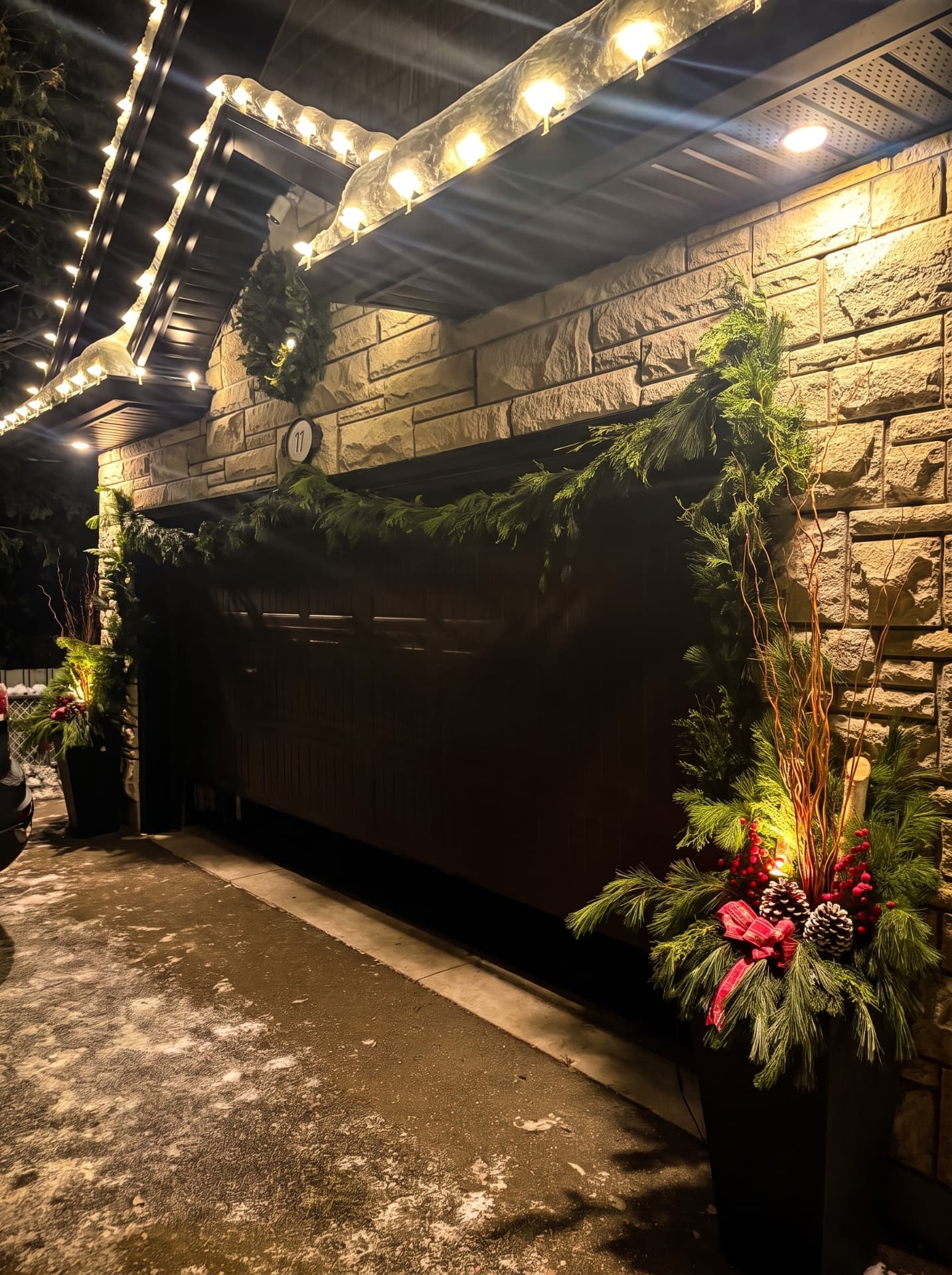 Covered driveway entry with fresh cedar garland, wreath and decorated winter urns
